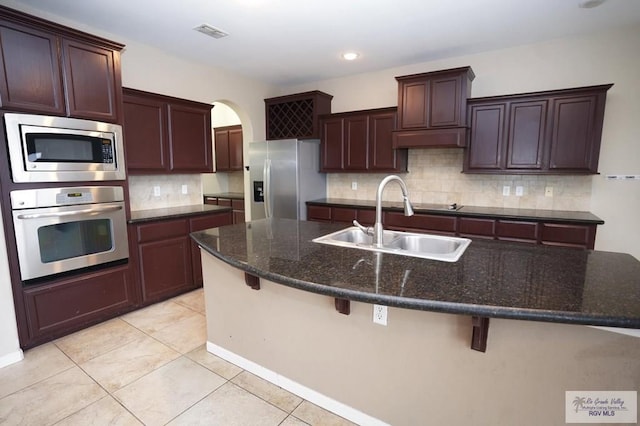 kitchen with a kitchen bar, stainless steel appliances, a center island with sink, and sink