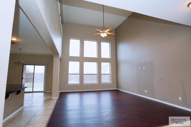 unfurnished room with ceiling fan with notable chandelier, wood-type flooring, and high vaulted ceiling