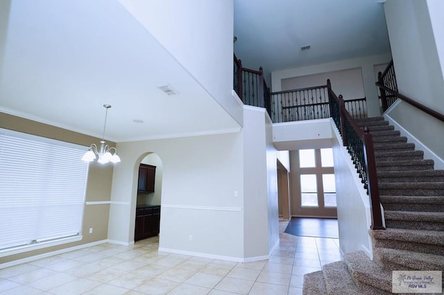 tiled entrance foyer featuring an inviting chandelier and crown molding