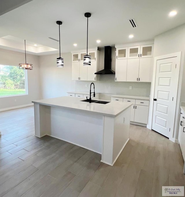 105 Republic Cir, San Benito, TX 78586 - kitchen featuring wall chimney exhaust hood, a sink, baseboards, a kitchen island with sink, and light wood-style flooring