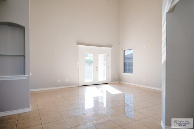 unfurnished room with light tile patterned floors, french doors, and a high ceiling