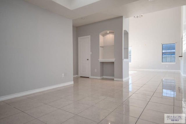 6724 Pino Verde Dr, Brownsville, TX 78526 - spare room featuring arched walkways, light tile patterned flooring, built in features, and baseboards