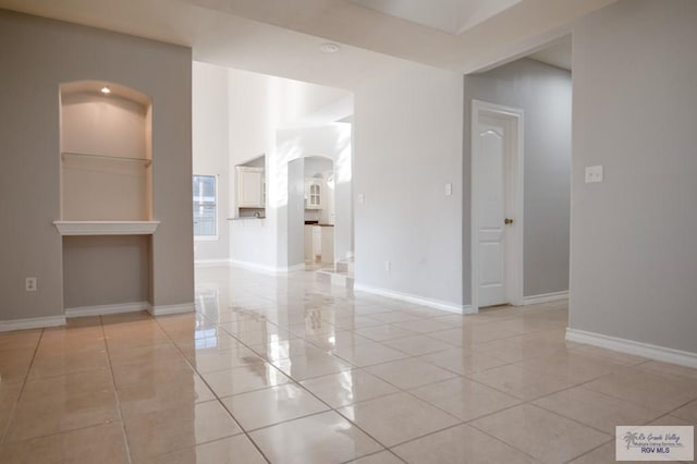 empty room with a fireplace and light tile patterned floors