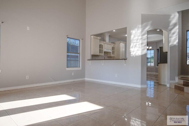 6724 Pino Verde Dr, Brownsville, TX 78526 - unfurnished room with a towering ceiling, light tile patterned floors, arched walkways, baseboards, and a chandelier