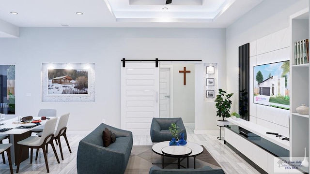 living room with a tray ceiling, a barn door, and light hardwood / wood-style floors