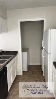 kitchen featuring dark countertops, white cabinets, freestanding refrigerator, and black dishwasher