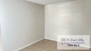 spare room with light tile patterned flooring and baseboards