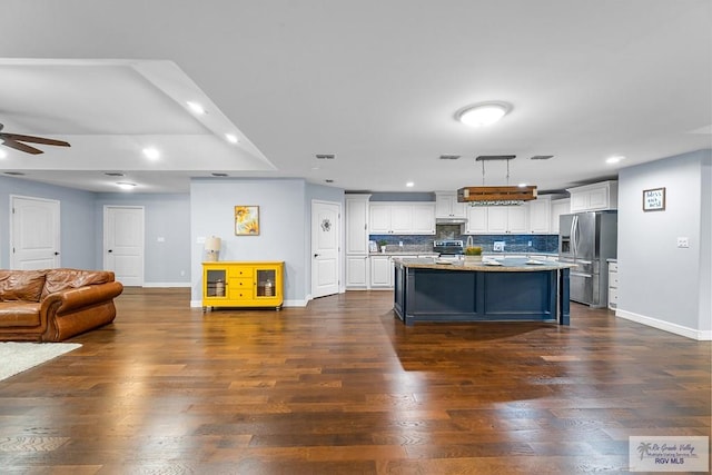 kitchen featuring white cabinetry, tasteful backsplash, hanging light fixtures, appliances with stainless steel finishes, and an island with sink