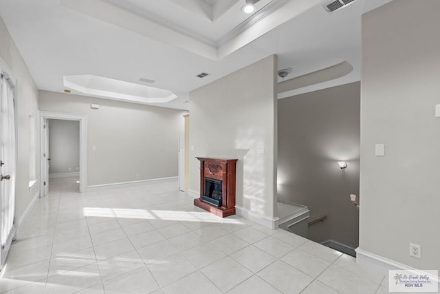 unfurnished living room featuring a tray ceiling, crown molding, and light tile patterned floors