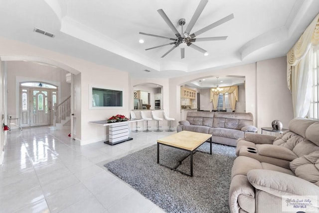 living room featuring ceiling fan with notable chandelier and a raised ceiling