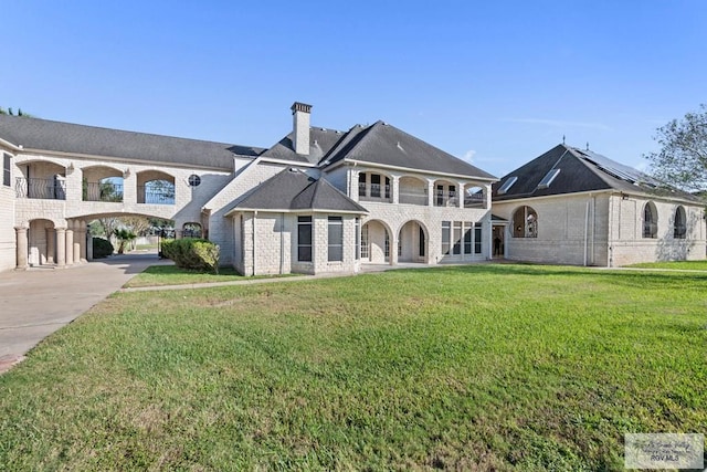 back of property featuring a lawn and a balcony