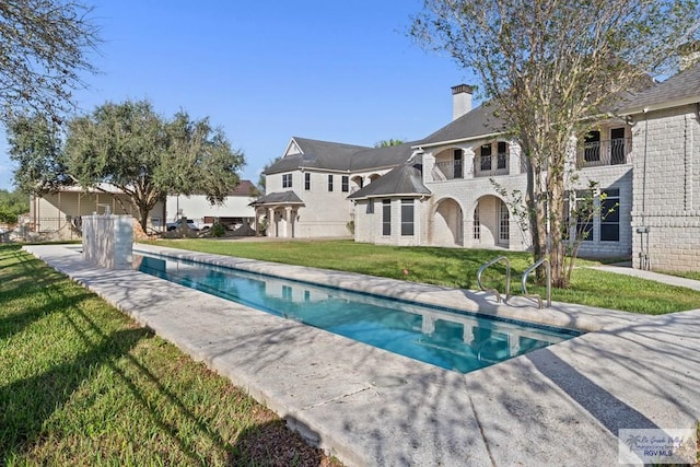 rear view of property with a lawn, a patio area, and a balcony