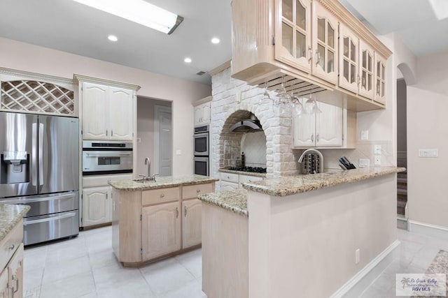 kitchen with light stone countertops, sink, an island with sink, and stainless steel appliances