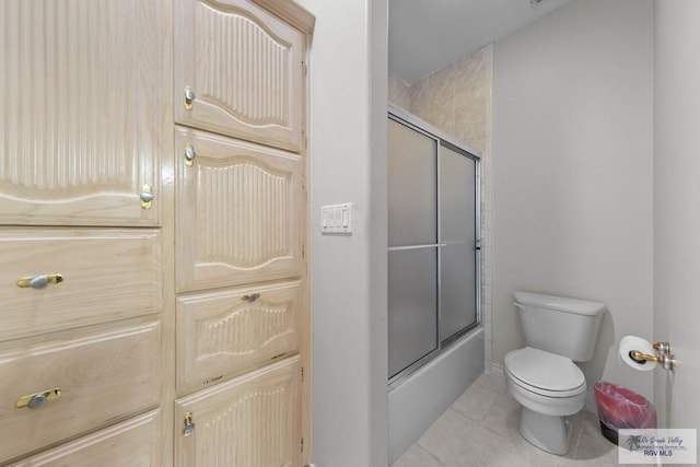 bathroom with toilet, tile patterned flooring, and combined bath / shower with glass door