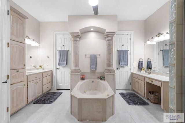 bathroom featuring tile patterned floors, vanity, ornate columns, and tiled tub