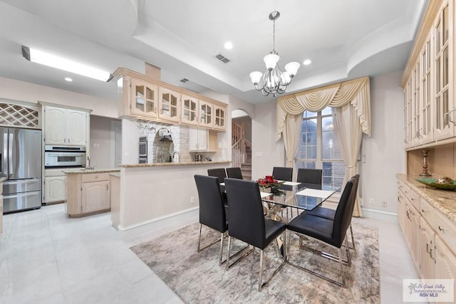 dining area featuring a notable chandelier, a raised ceiling, ornamental molding, and sink