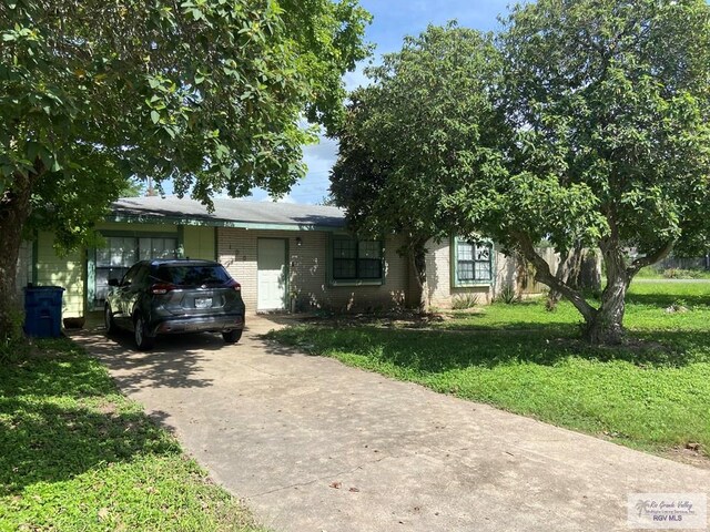 100 Pine St, Los Fresnos, TX 78566 - view of front of home with brick siding, a front yard, and driveway