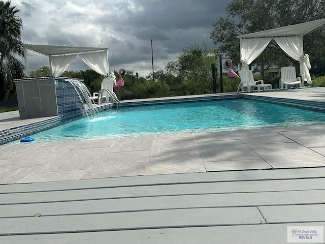 view of pool with pool water feature and a patio