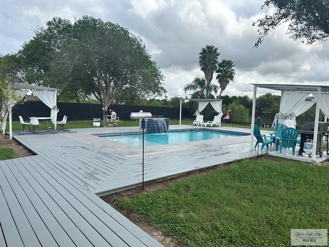 view of swimming pool featuring pool water feature, a yard, a deck, and grilling area