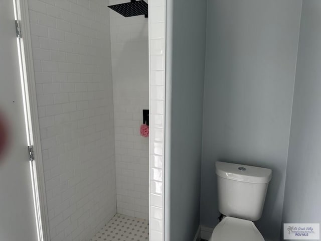 bathroom with a tile shower and toilet