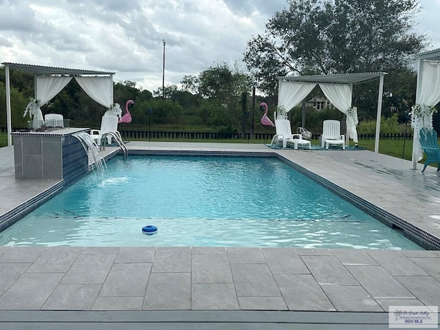 view of swimming pool with pool water feature and a patio