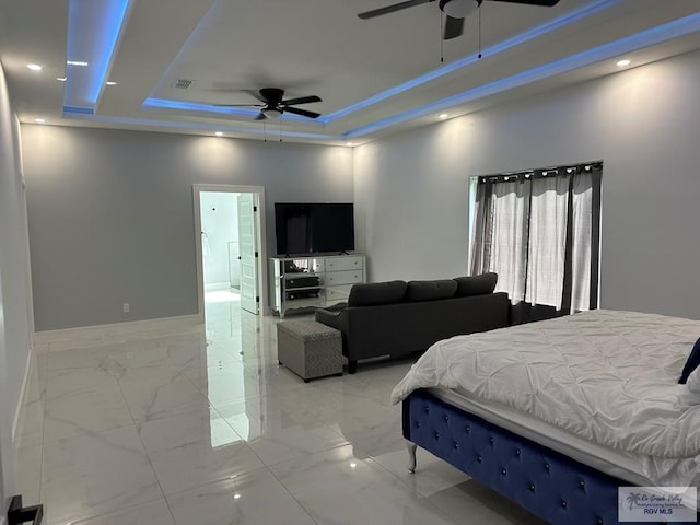 bedroom featuring ceiling fan, ensuite bathroom, and a tray ceiling