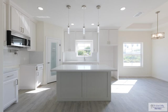 kitchen featuring a kitchen island, white cabinetry, and a healthy amount of sunlight