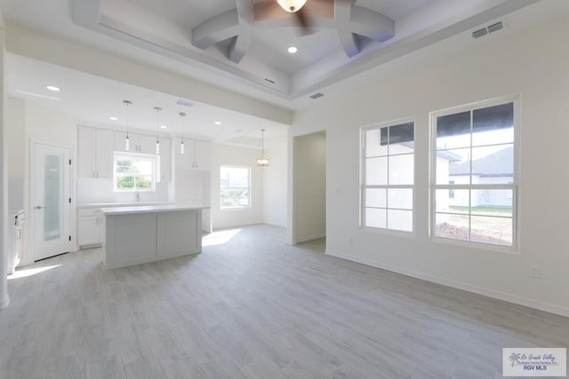 unfurnished living room with ceiling fan, beam ceiling, and light wood-type flooring