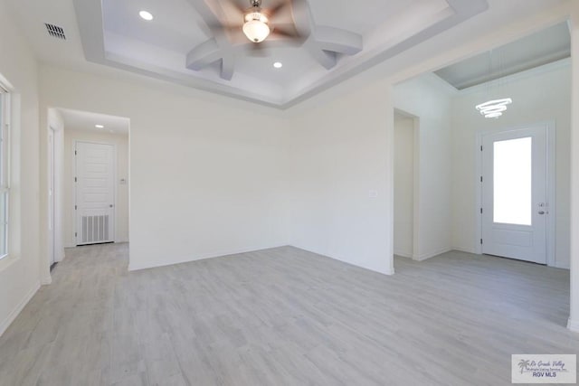 spare room with a tray ceiling, light hardwood / wood-style flooring, and ceiling fan with notable chandelier