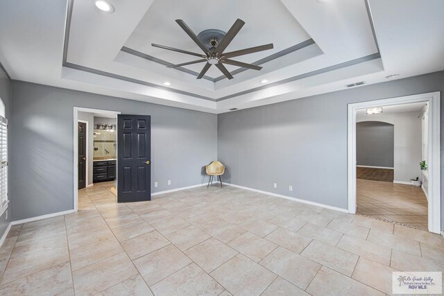 empty room featuring a raised ceiling and ceiling fan