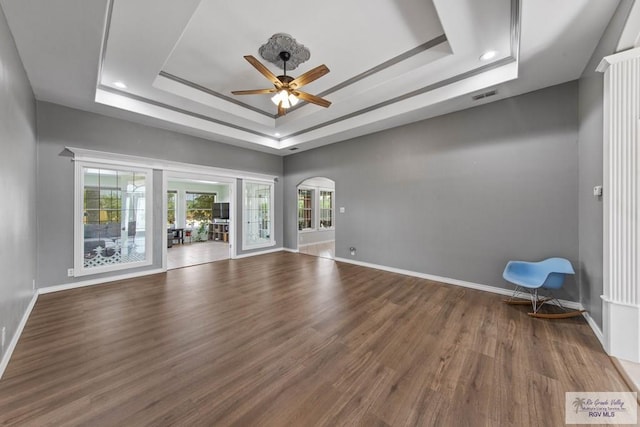 empty room with hardwood / wood-style flooring, ceiling fan, and a raised ceiling