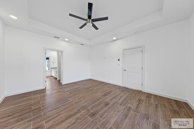 empty room featuring hardwood / wood-style floors, ceiling fan, and a tray ceiling