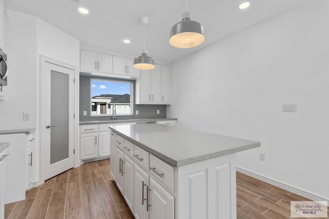 kitchen with white cabinets, light wood-type flooring, and a center island