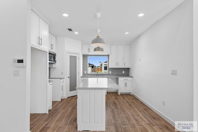 kitchen with white cabinetry, hanging light fixtures, and dark wood-type flooring