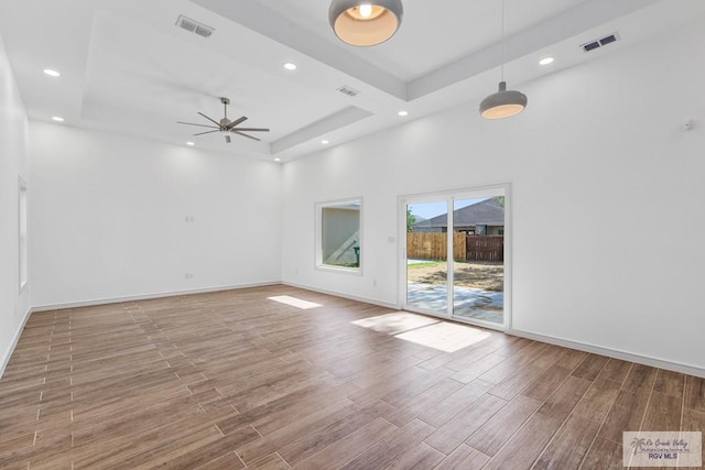 spare room featuring a towering ceiling, hardwood / wood-style flooring, ceiling fan, and a tray ceiling