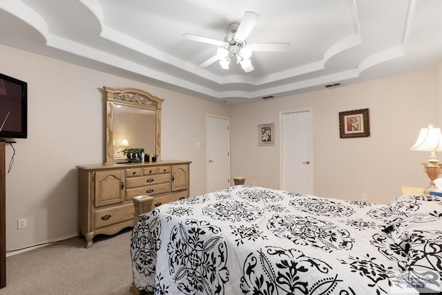 bedroom with ceiling fan, light carpet, and a tray ceiling