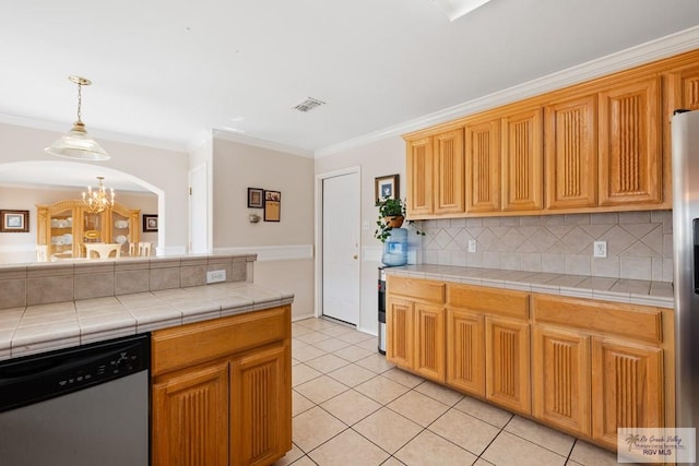 kitchen with tasteful backsplash, ornamental molding, stainless steel appliances, an inviting chandelier, and tile counters