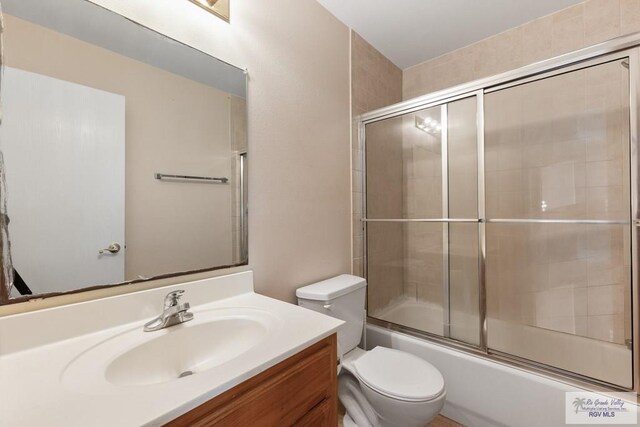 full bathroom with shower / bath combination with glass door, vanity, and toilet