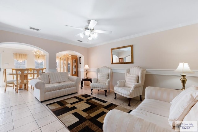 living room with light tile patterned floors, ceiling fan with notable chandelier, and crown molding