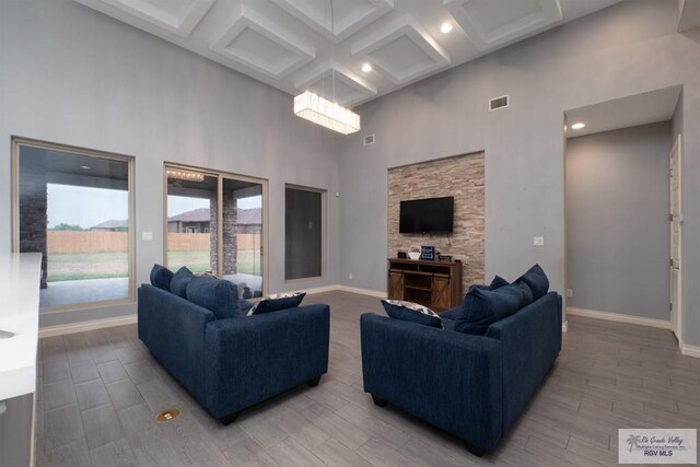 living room featuring hardwood / wood-style floors, a towering ceiling, beamed ceiling, and coffered ceiling