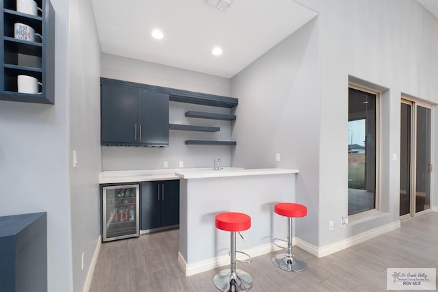 bar featuring beverage cooler and light hardwood / wood-style flooring