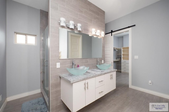 bathroom with tile walls, vanity, wood-type flooring, and an enclosed shower