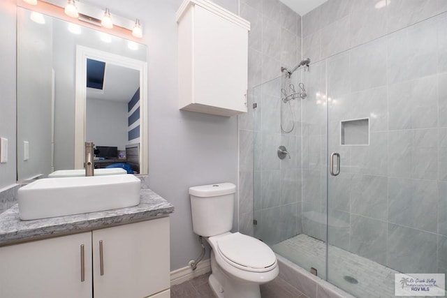 bathroom featuring vanity, a shower with shower door, and toilet