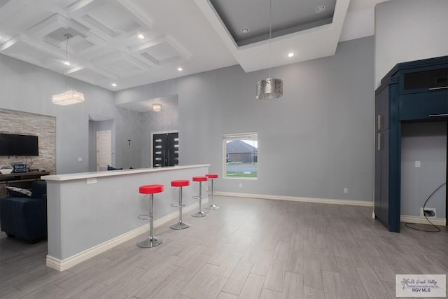 kitchen with a kitchen bar, hanging light fixtures, a high ceiling, and light wood-type flooring