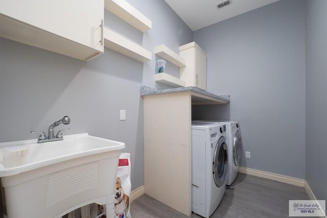 laundry room featuring dark hardwood / wood-style flooring, cabinets, independent washer and dryer, and sink