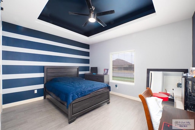 bedroom with hardwood / wood-style flooring, ceiling fan, and a tray ceiling