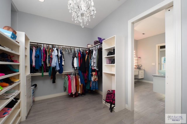 spacious closet featuring a chandelier and light wood-type flooring