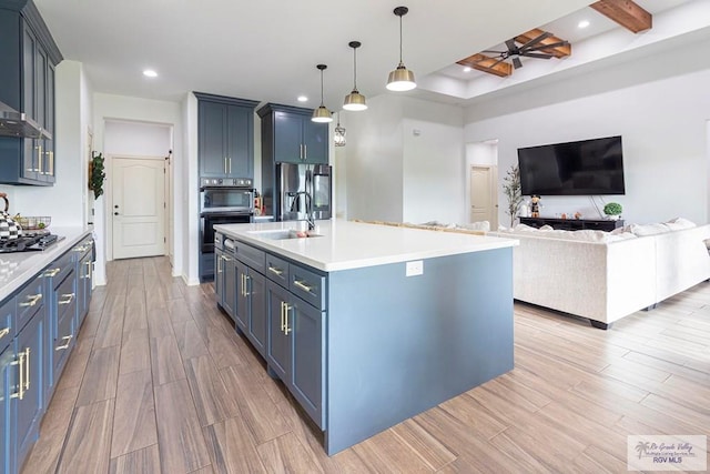 kitchen featuring blue cabinets, sink, ceiling fan, an island with sink, and light hardwood / wood-style floors