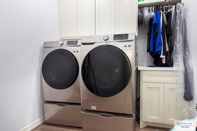 laundry area featuring cabinets, hardwood / wood-style floors, and washer and dryer