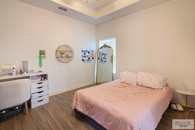 bedroom featuring dark hardwood / wood-style flooring and a tray ceiling